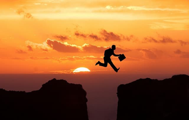夕日をバックにジャンプしているサラーリーマンの画像
